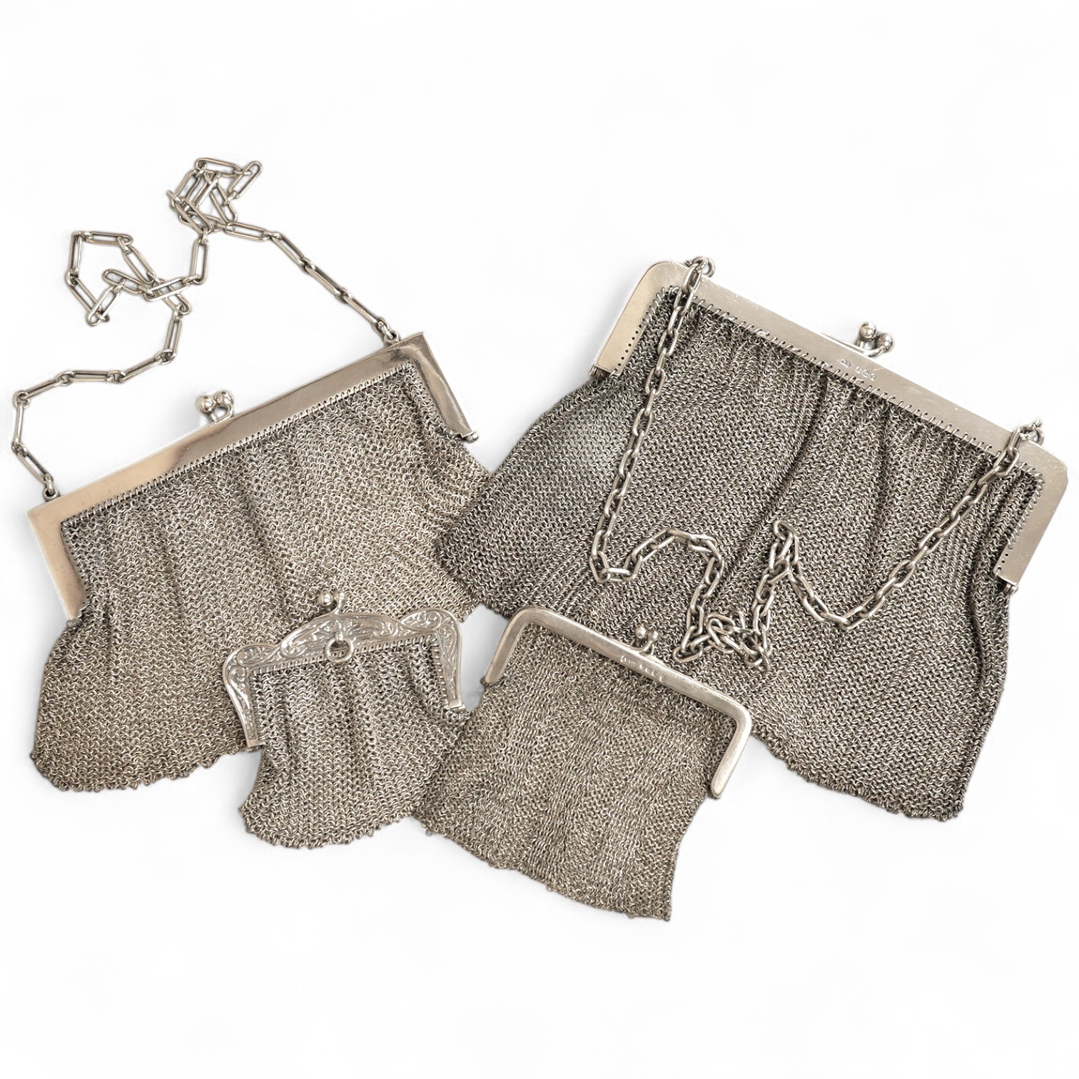 A George V silver mesh evening bag, import marks for Paul Ettlinger, London, 1932, a similar small evening purse, import marks for London, 1919 and two other white metal mesh evening bags or purses, one stamped sterling.